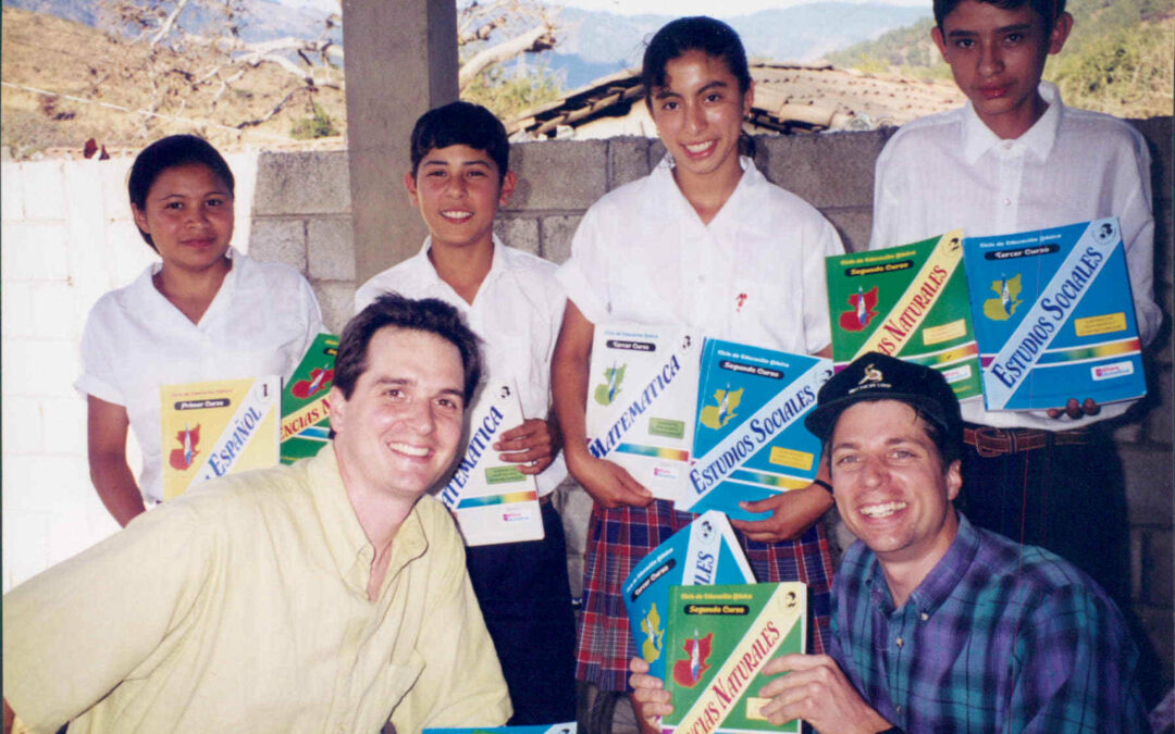 Brothers Jeff (front left) and Joe (front right) crouched in front of group of students, all holding textbooks.