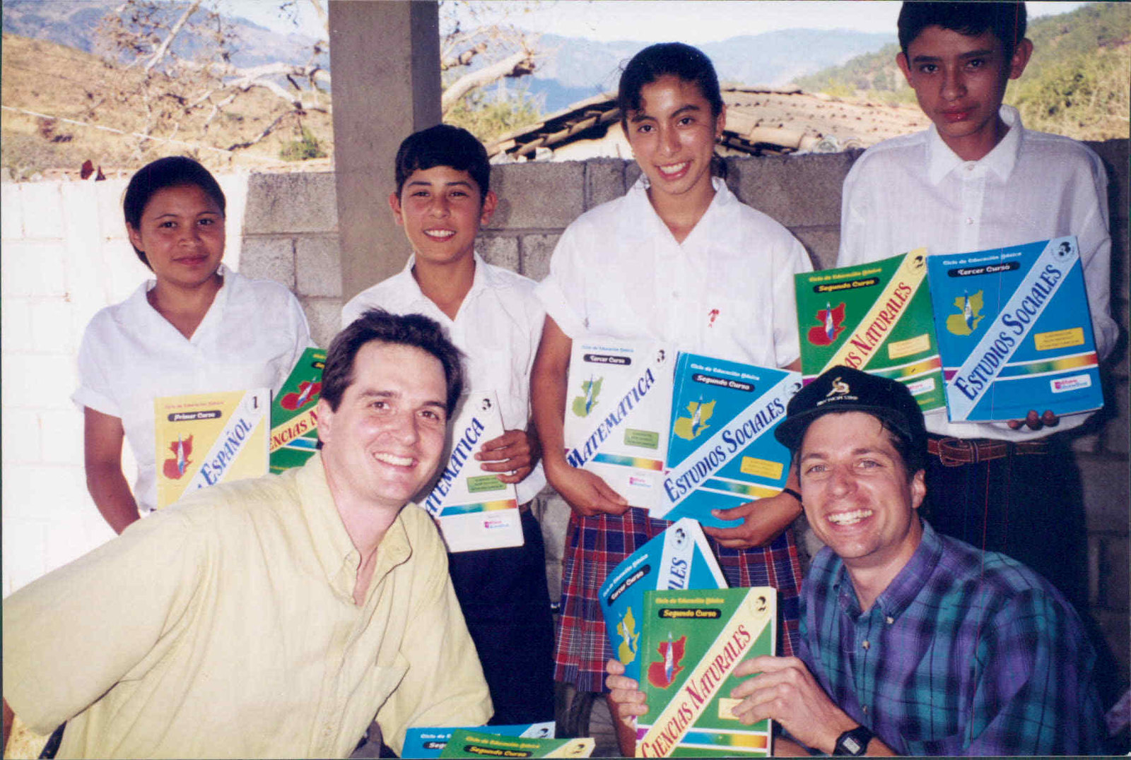 Brothers Jeff (front left) and Joe (front right) crouched in front of group of students, all holding textbooks.