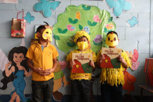 Elementary age Spark reading program students, dressed in fun chicken costumes to engage in reading a children's story together in the classroom